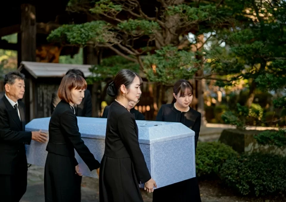 棺を運ぶ喪服姿の人々