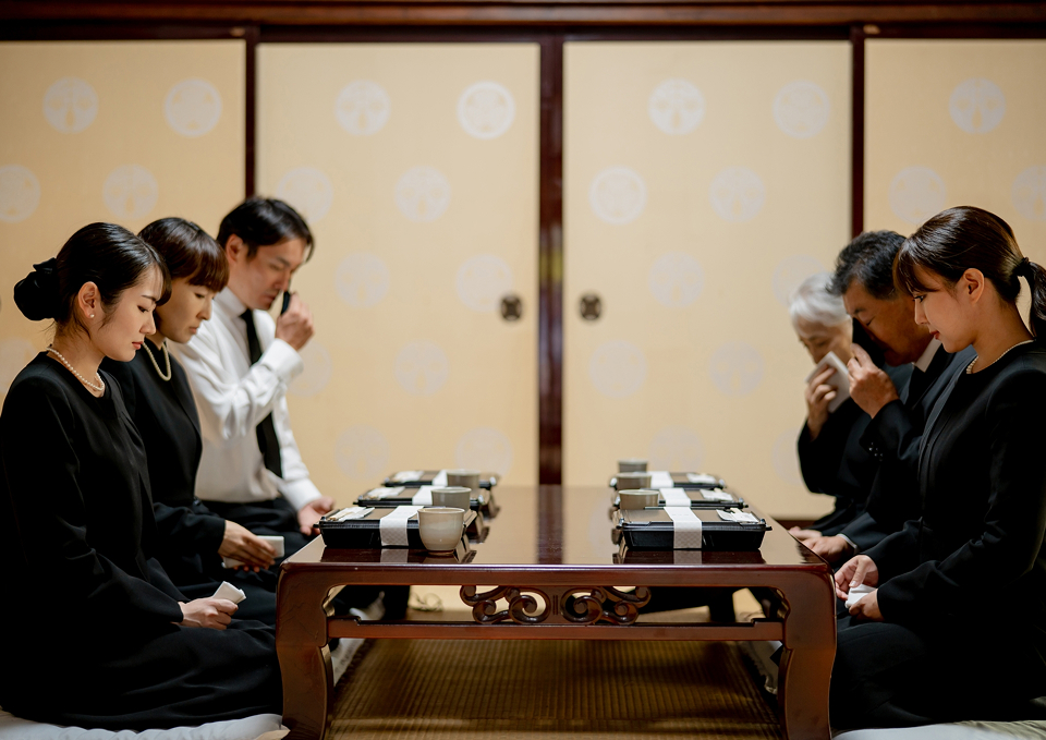 和室で会食をする喪服姿の家族