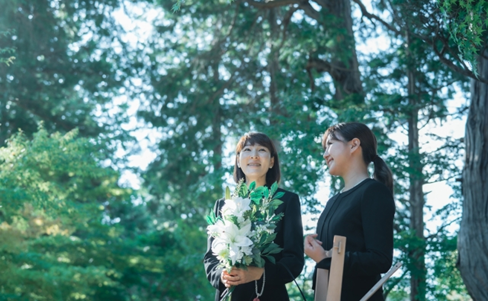 白い花束を持つ喪服姿の女性2人