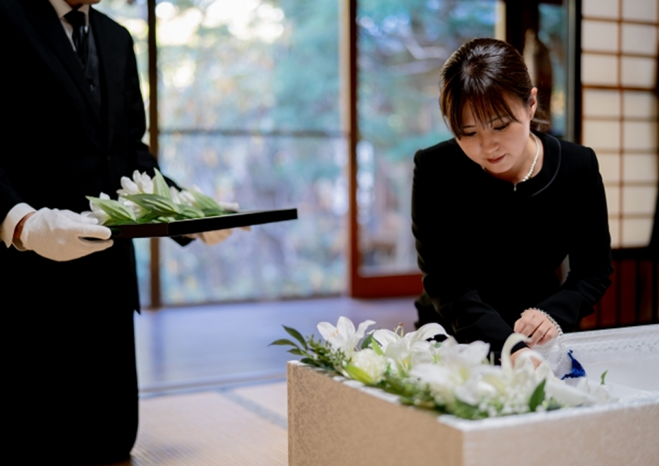 棺に花を手向ける喪服姿の女性